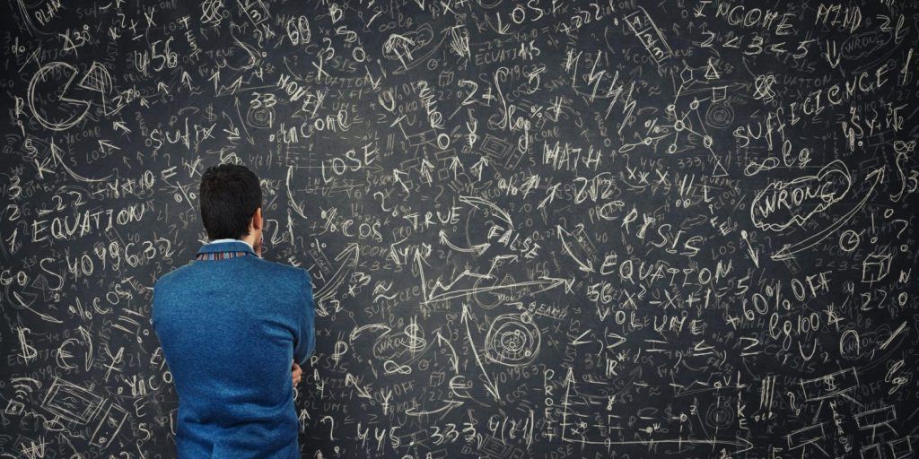 Man staring at gobbled gook on a black board.
