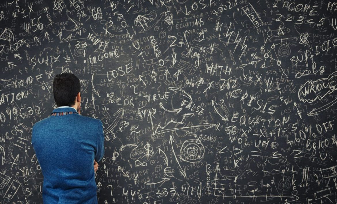 Man staring at gobbled gook on a black board.