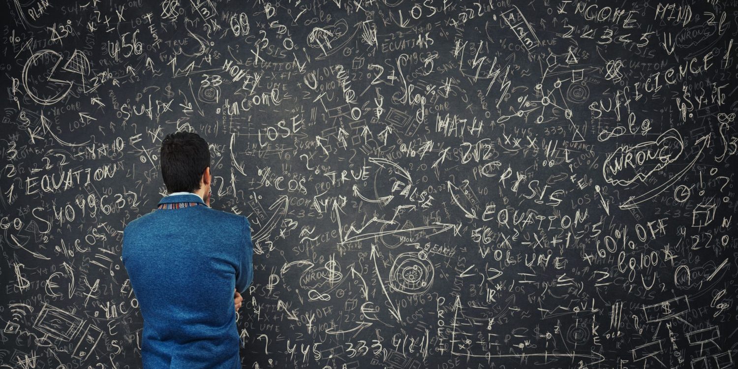 Man staring at gobbled gook on a black board.